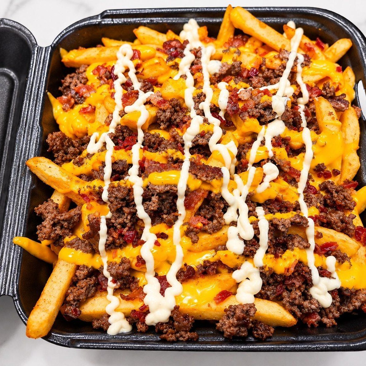 Bacon Cheeseburger Fries loaded with seasoned beef, melted cheese, bacon bits and drizzled sauce